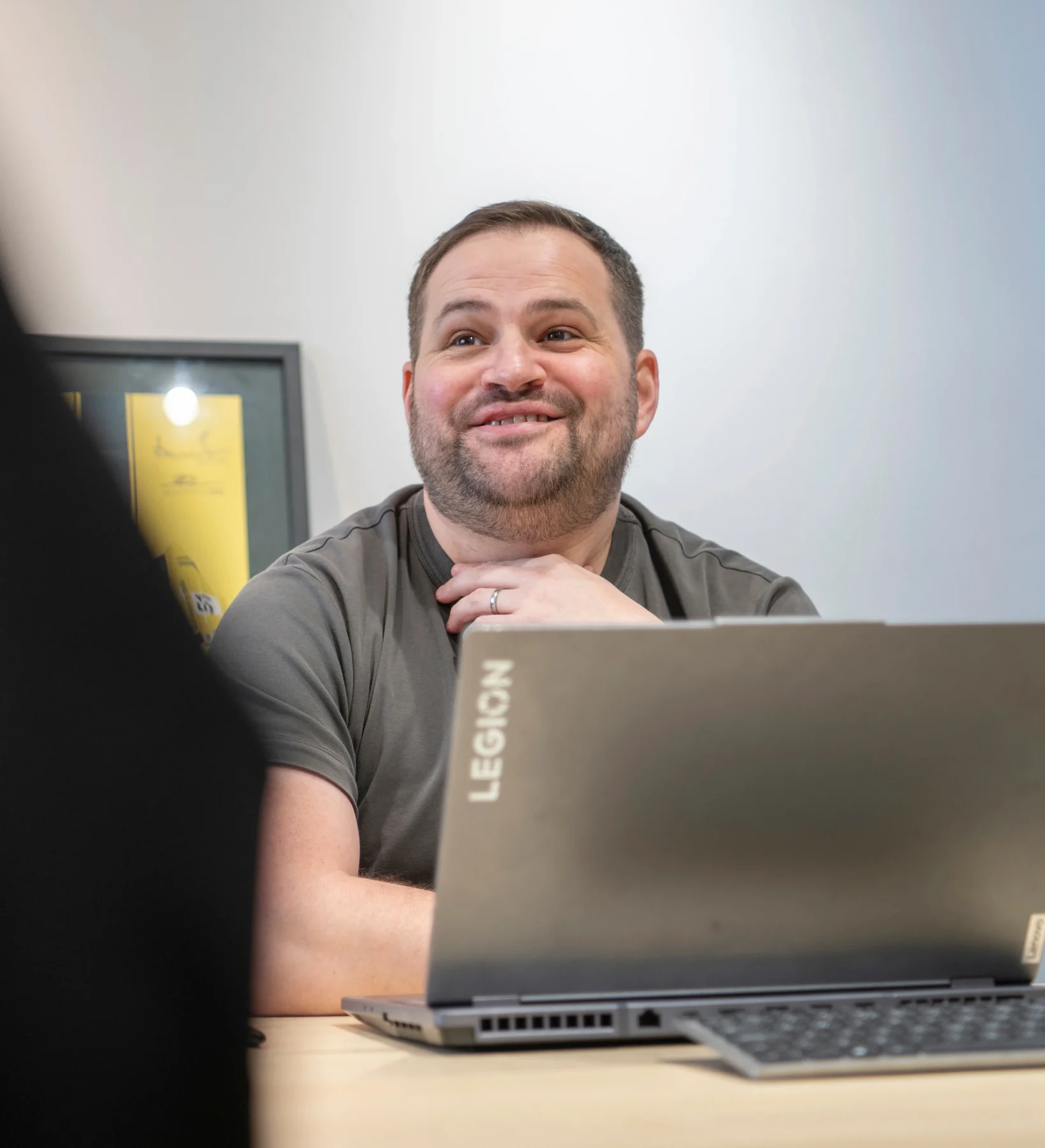 Taran's Alex smiling while sitting at a desk with a Lenovo laptop during an office IT consultation.
