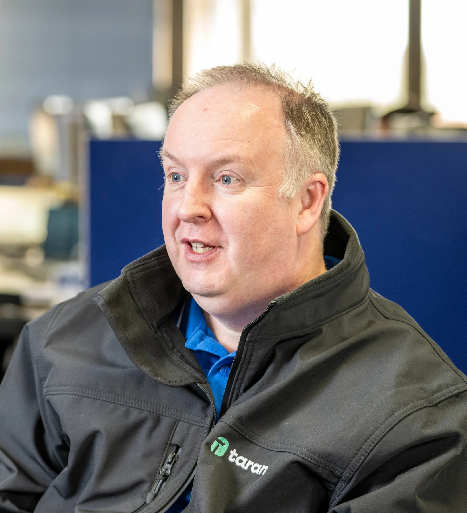 Taran IT consultant speaking while seated in the office.