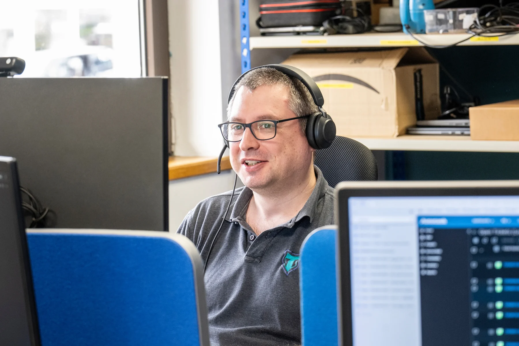 IT support engineer at Taran wearing a headset while monitoring systems at a workstation in the office.